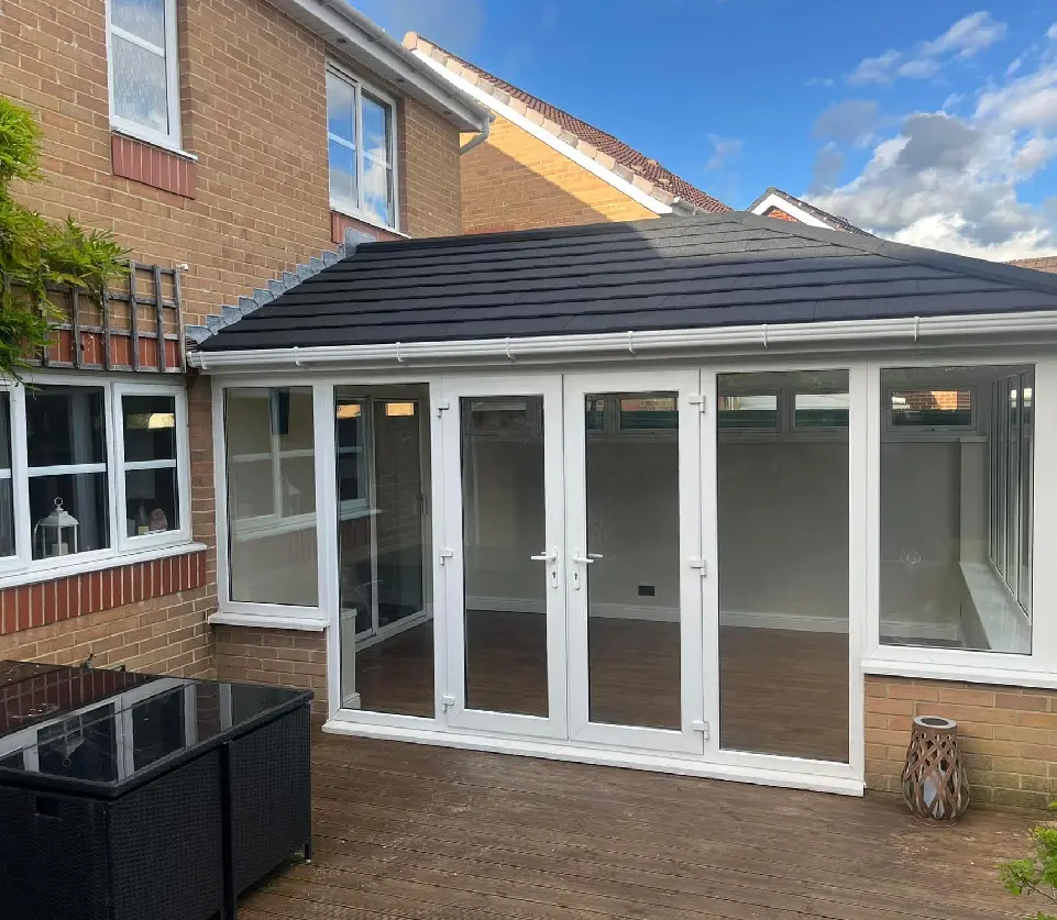 A large patio with glass doors and a black roof.